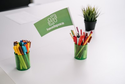 coloured markers and pencils in a green pencil holder, on a table. 
