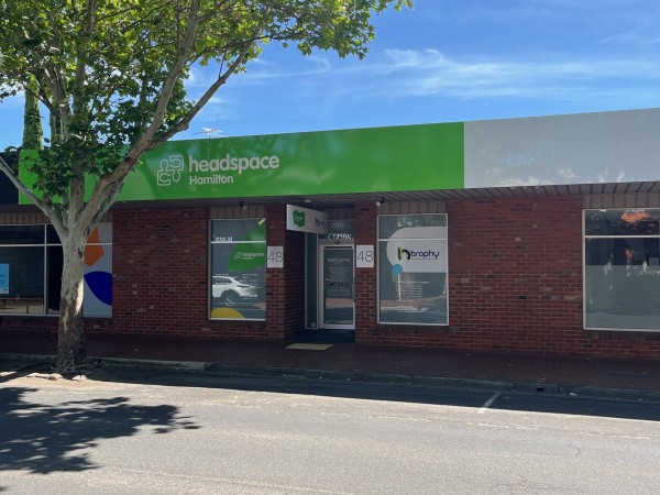A brown brick building on the street with a headspace Hamilton sign and a Brophy sign