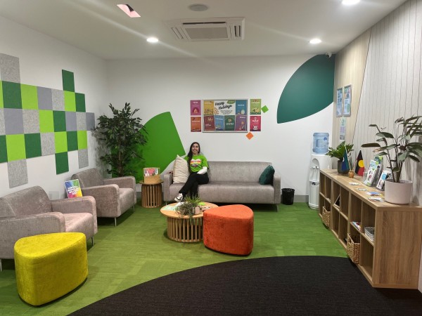 A large room with couches, a coffee table, water dispenser and shelving