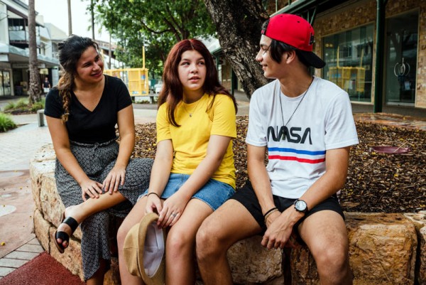 Three young people sitting outside engaging in conversation